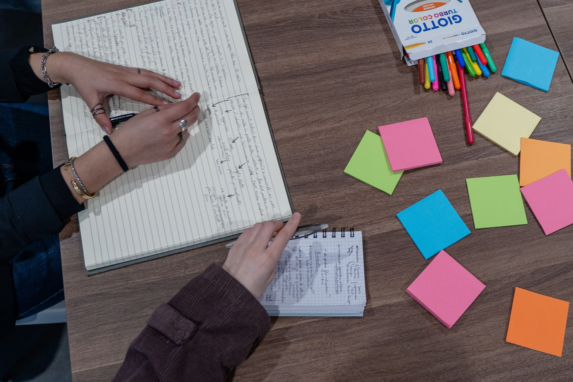 Mani che lavorano su appunti e idee durante un workshop